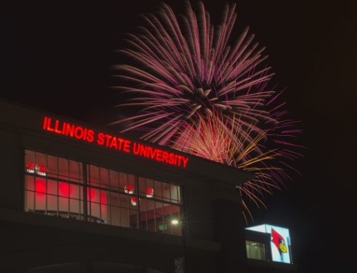 Fireworks are visible above Hancock Stadium and the Aaron Leetch Club room where lighted letters spell out "Illinois State University"